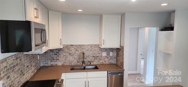 kitchen with appliances with stainless steel finishes, sink, white cabinets, and backsplash