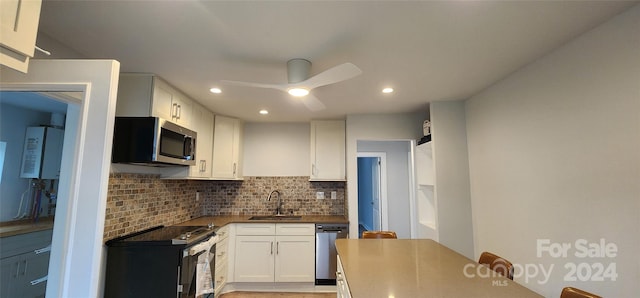 kitchen featuring decorative backsplash, water heater, stainless steel appliances, sink, and white cabinets