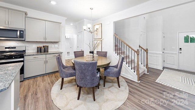 dining area featuring hardwood / wood-style floors, crown molding, and a chandelier