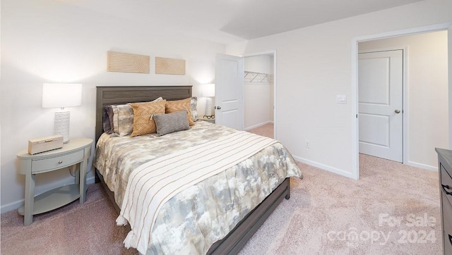 carpeted bedroom featuring a walk in closet and a closet