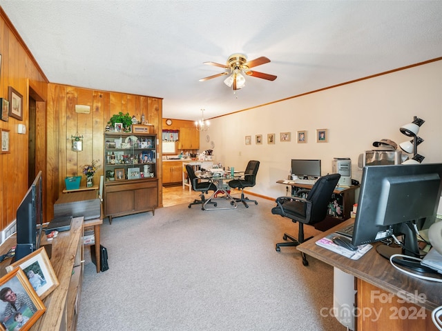 office area featuring a textured ceiling, wood walls, ceiling fan with notable chandelier, crown molding, and light colored carpet