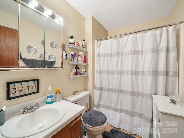 bathroom featuring toilet, a textured ceiling, curtained shower, and vanity