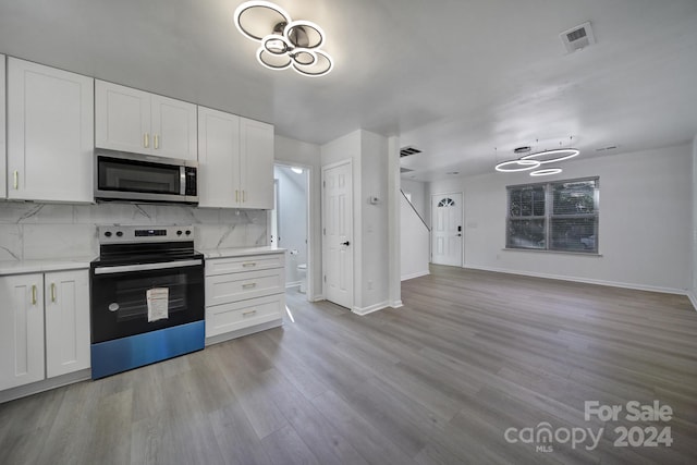 kitchen featuring decorative backsplash, appliances with stainless steel finishes, white cabinetry, and light hardwood / wood-style floors