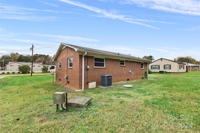 rear view of house featuring central air condition unit and a lawn