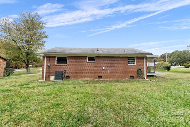 back of house with cooling unit and a lawn