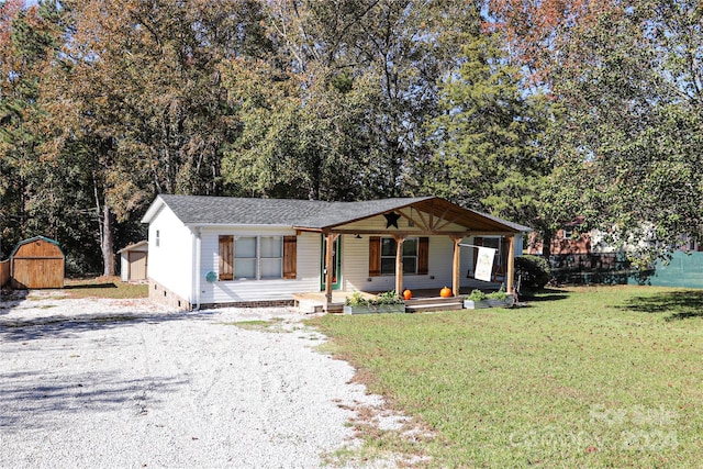 view of front of home with a storage shed, a front yard, and a porch