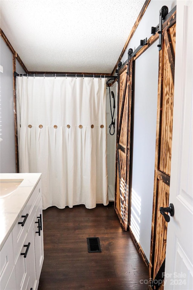 bathroom featuring a textured ceiling, hardwood / wood-style flooring, ornamental molding, vanity, and a shower with shower curtain