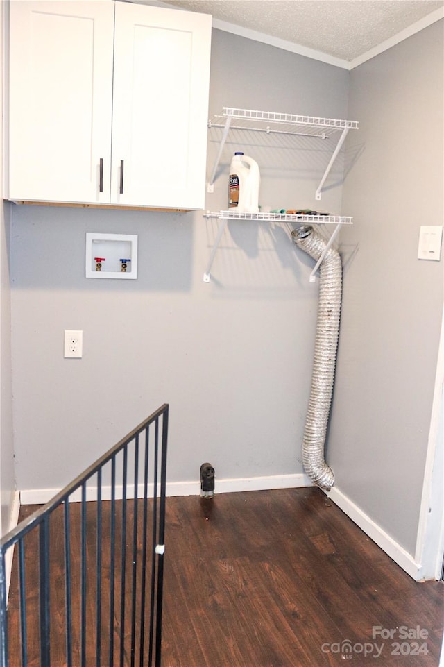 clothes washing area with dark wood-type flooring, hookup for a washing machine, crown molding, cabinets, and a textured ceiling