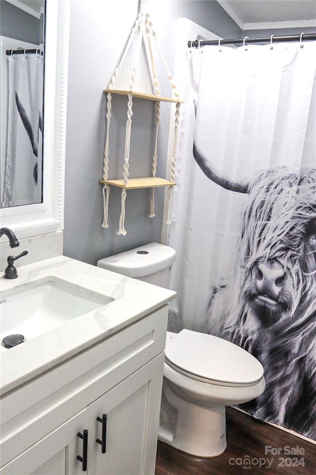 bathroom with hardwood / wood-style flooring, toilet, crown molding, vanity, and walk in shower