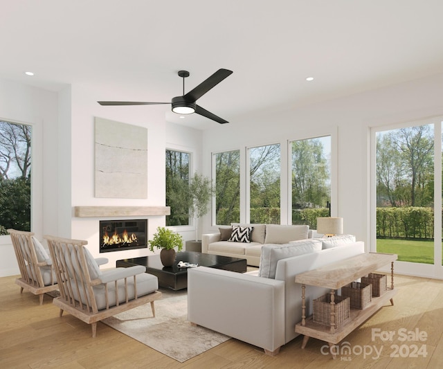 living room with light hardwood / wood-style flooring, a large fireplace, and ceiling fan