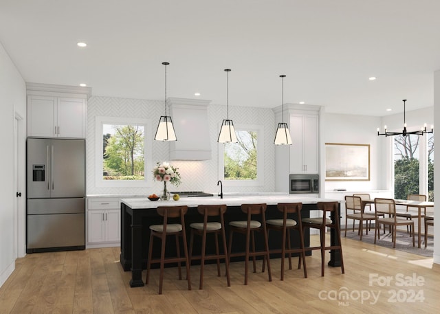 kitchen with hanging light fixtures, a breakfast bar, a center island, appliances with stainless steel finishes, and light hardwood / wood-style floors