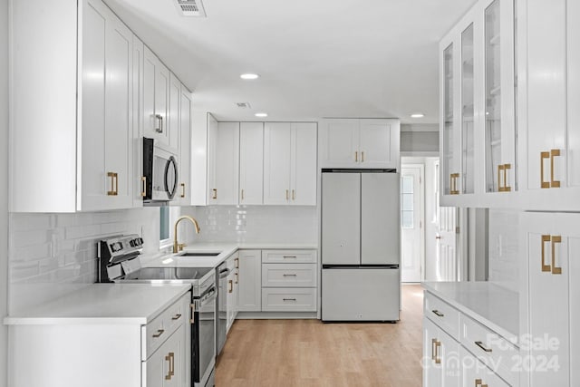 kitchen featuring stainless steel appliances, sink, light wood-type flooring, and white cabinets