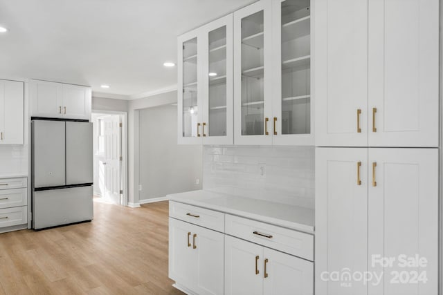 kitchen featuring light hardwood / wood-style flooring, white fridge, white cabinets, and tasteful backsplash