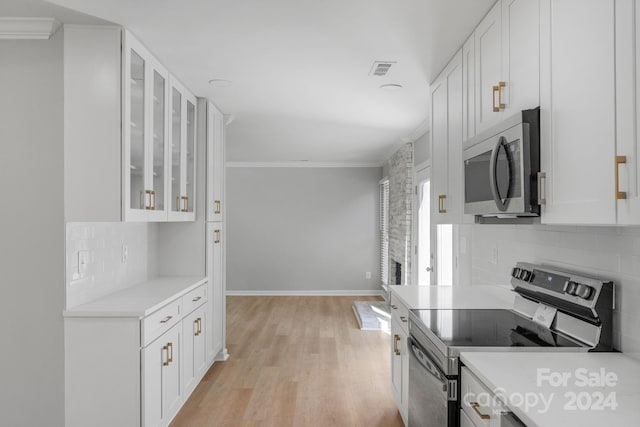 kitchen featuring crown molding, white cabinets, stainless steel appliances, and light wood-type flooring