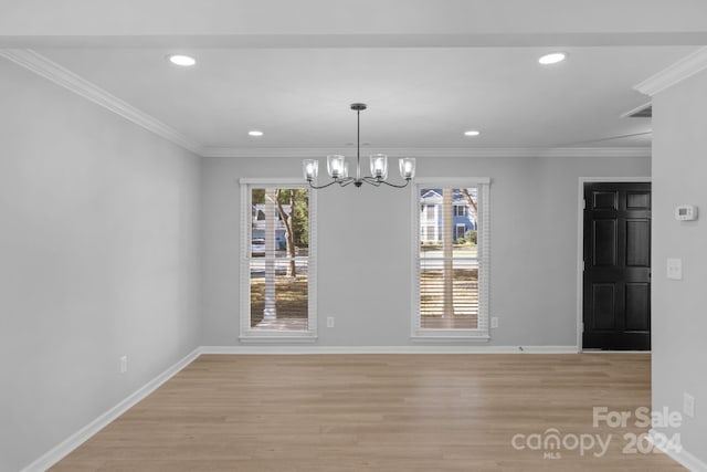 unfurnished dining area with crown molding, light hardwood / wood-style flooring, and a chandelier