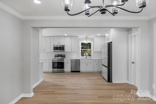 kitchen featuring crown molding, appliances with stainless steel finishes, light wood-type flooring, and white cabinets