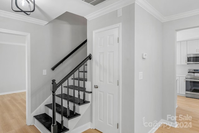 staircase with ornamental molding and hardwood / wood-style floors