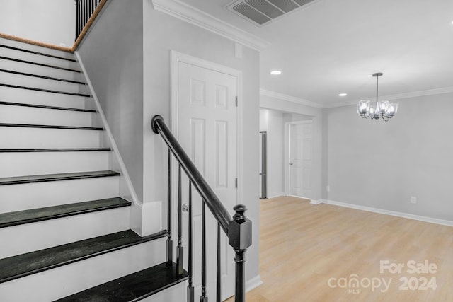 staircase with a notable chandelier, ornamental molding, and hardwood / wood-style flooring