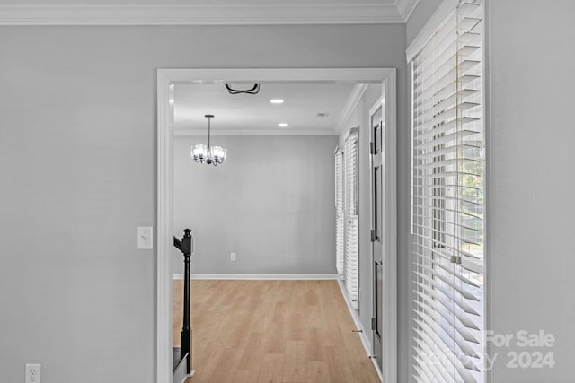 hallway featuring light hardwood / wood-style floors, crown molding, and a chandelier