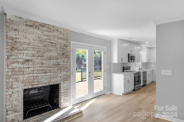 kitchen featuring tasteful backsplash, appliances with stainless steel finishes, light wood-type flooring, and white cabinets