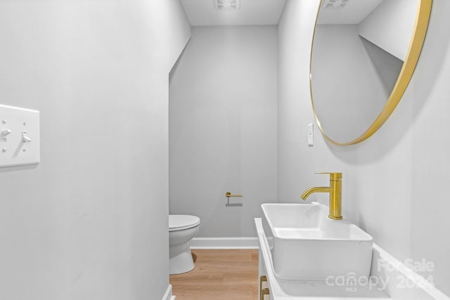 bathroom with toilet, sink, and hardwood / wood-style floors