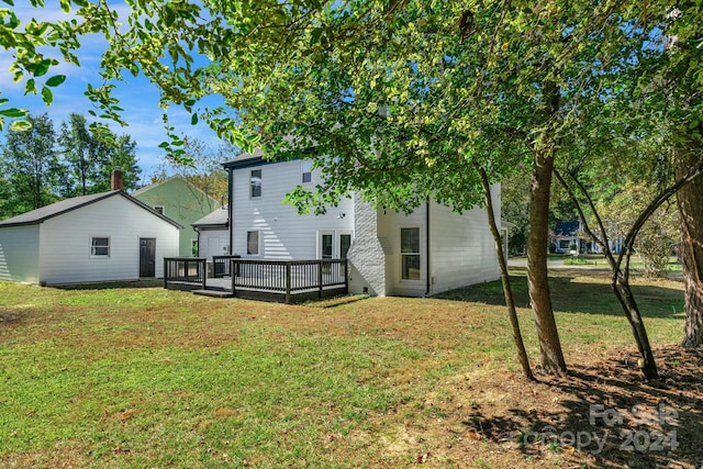 rear view of house with a wooden deck and a lawn