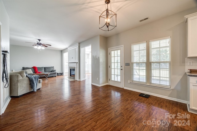 living room featuring ceiling fan with notable chandelier and dark hardwood / wood-style flooring