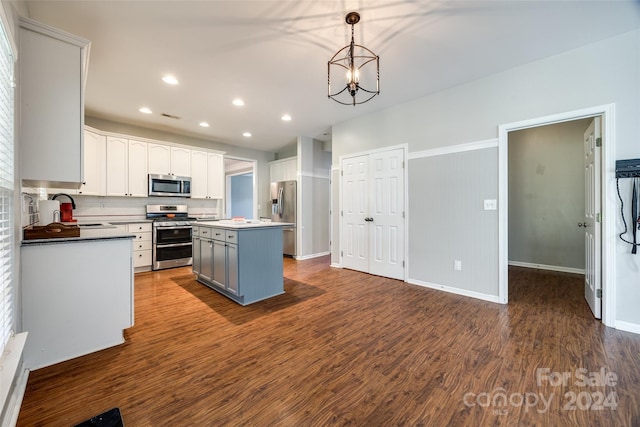 kitchen with dark hardwood / wood-style flooring, stainless steel appliances, a center island, white cabinetry, and hanging light fixtures