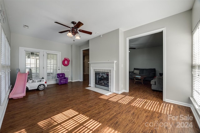 unfurnished living room featuring a tiled fireplace, ceiling fan, and dark hardwood / wood-style flooring