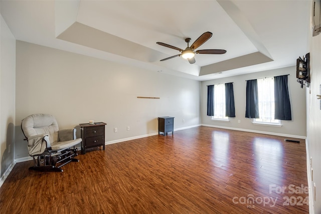 sitting room with hardwood / wood-style floors, ceiling fan, and a tray ceiling