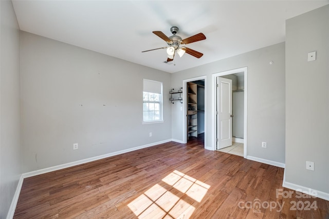 unfurnished bedroom featuring a spacious closet, ceiling fan, light hardwood / wood-style flooring, ensuite bathroom, and a closet