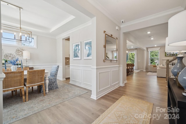 dining room with light hardwood / wood-style floors, ornamental molding, a chandelier, and a barn door