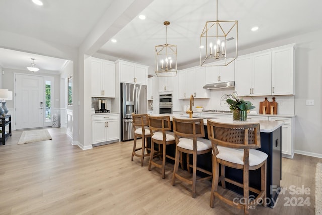 kitchen featuring a center island with sink, pendant lighting, light hardwood / wood-style flooring, and stainless steel appliances