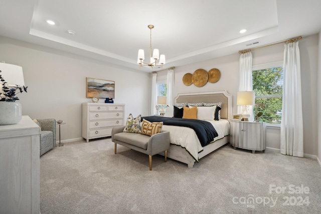 carpeted bedroom featuring a notable chandelier and a tray ceiling