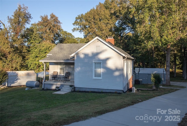 back of property with covered porch and a lawn