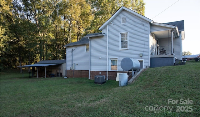 rear view of house with a carport, central air condition unit, and a lawn