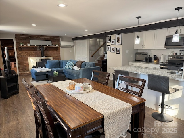 dining area with dark wood-type flooring, a wall unit AC, and a wood stove