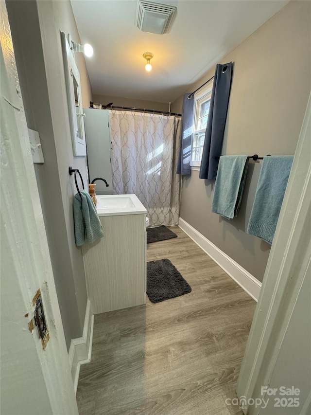 bathroom with hardwood / wood-style flooring, vanity, and walk in shower