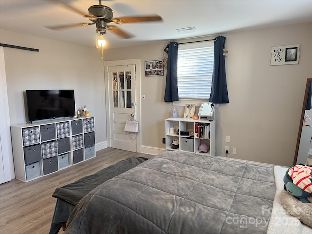 bedroom with dark hardwood / wood-style flooring, a barn door, and ceiling fan