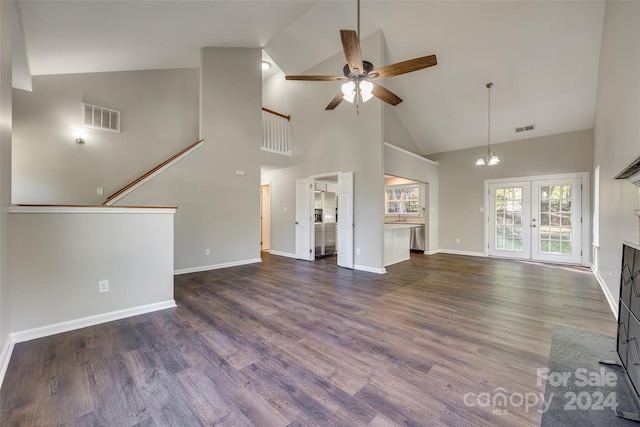 unfurnished living room featuring ceiling fan with notable chandelier, high vaulted ceiling, and dark hardwood / wood-style floors