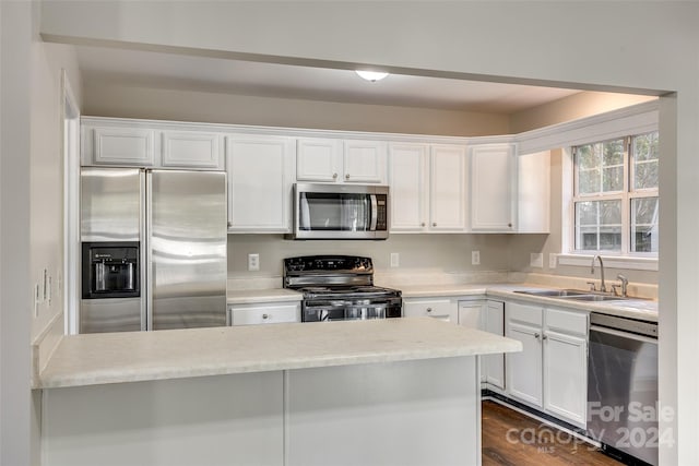 kitchen with appliances with stainless steel finishes, white cabinets, sink, and dark hardwood / wood-style flooring