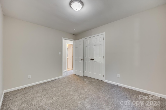 unfurnished bedroom with a closet and light carpet