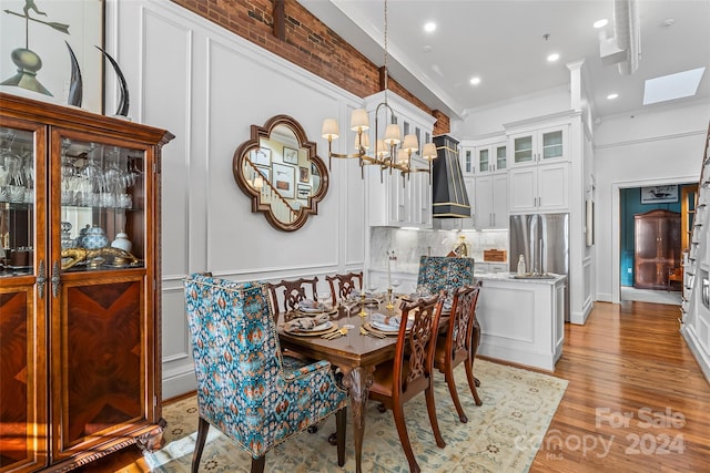 dining area with a chandelier, crown molding, light wood-type flooring, and a skylight