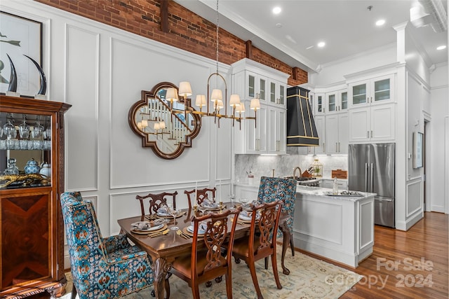 dining area with sink, crown molding, wood-type flooring, and an inviting chandelier