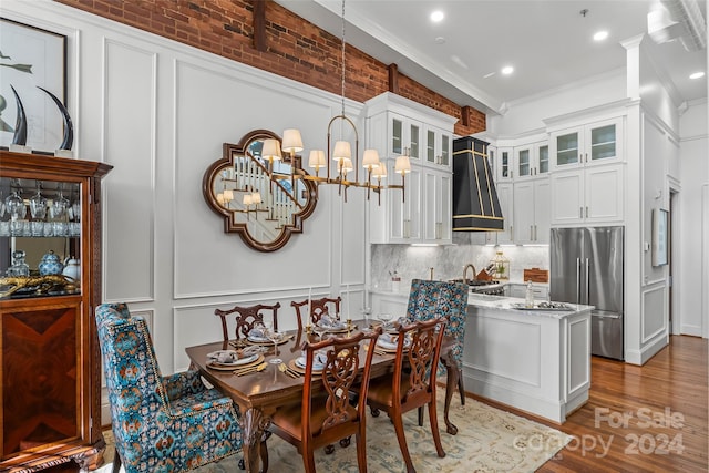 dining room with wood finished floors, a decorative wall, crown molding, and an inviting chandelier