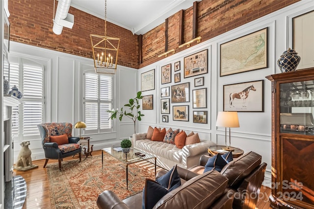 living area with wood finished floors, a chandelier, ornamental molding, and a decorative wall