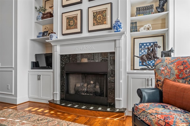 sitting room featuring built in features, hardwood / wood-style flooring, and a fireplace