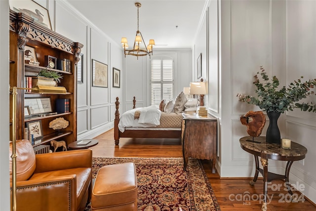 sitting room with crown molding, hardwood / wood-style flooring, and an inviting chandelier