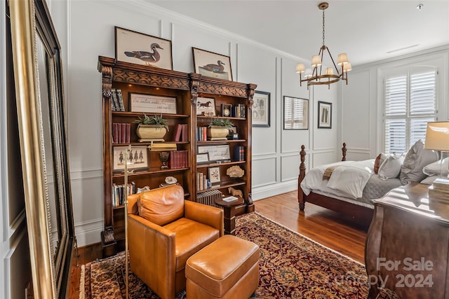 interior space featuring wood finished floors, a chandelier, ornamental molding, and a decorative wall