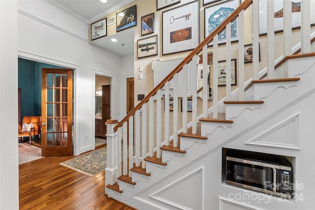 stairway featuring ornamental molding and hardwood / wood-style flooring